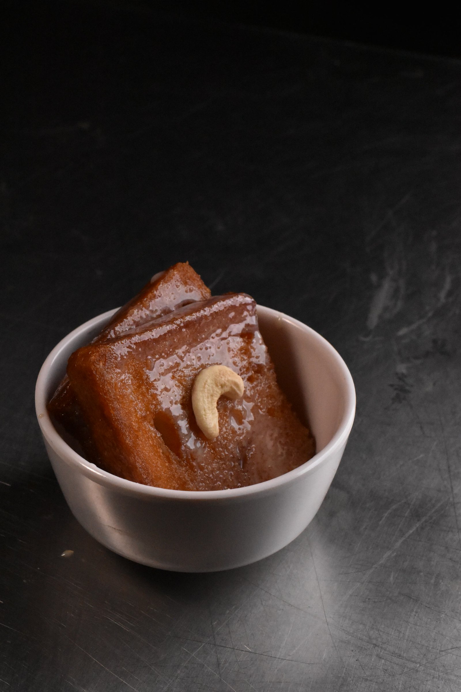 Double ka meetha, bread soaked in sweetened milk and topped with a cashew, served in a white bowl