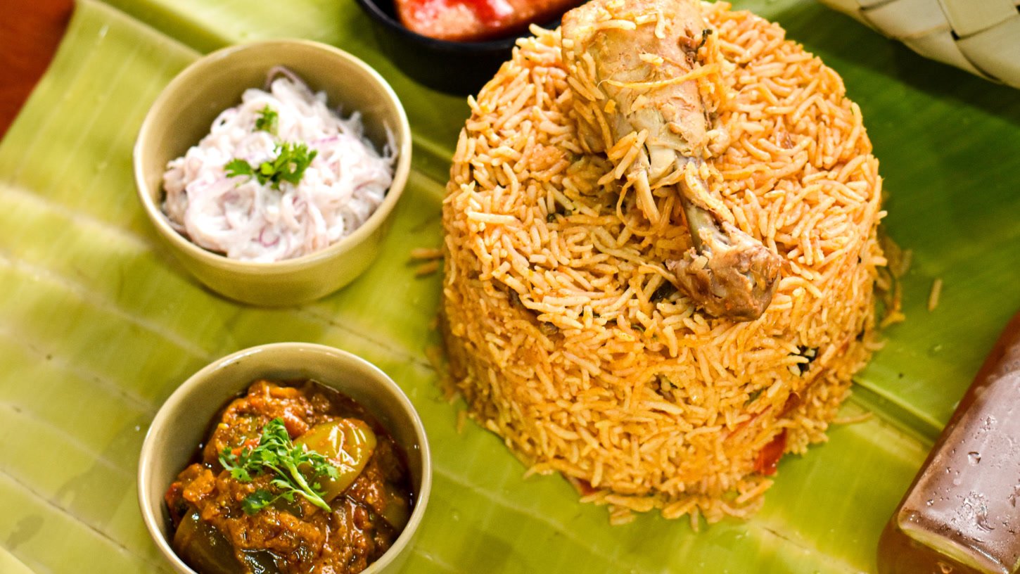 Biriyani with a whole chicken leg, raita and brinjal curry